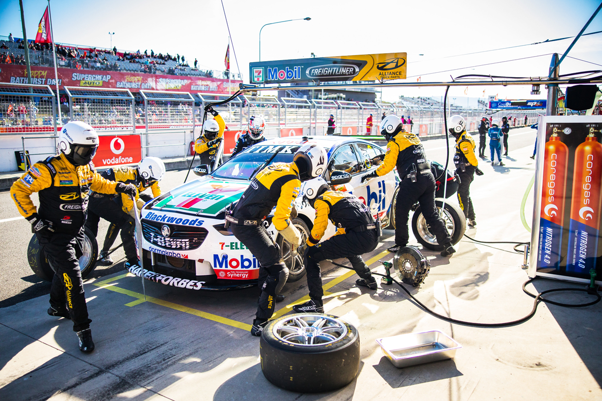 A motorsport pit crew working on a car during a race stop